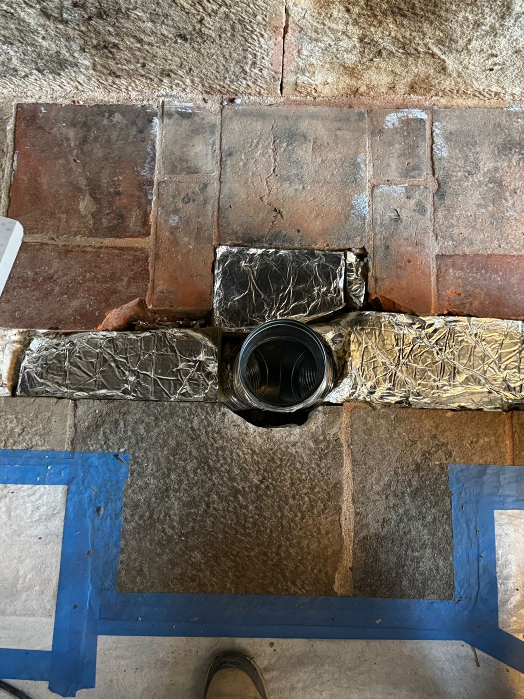 Combustion air supply of the masonry heater opening at floor level in the old fireplace, between the original flagstones