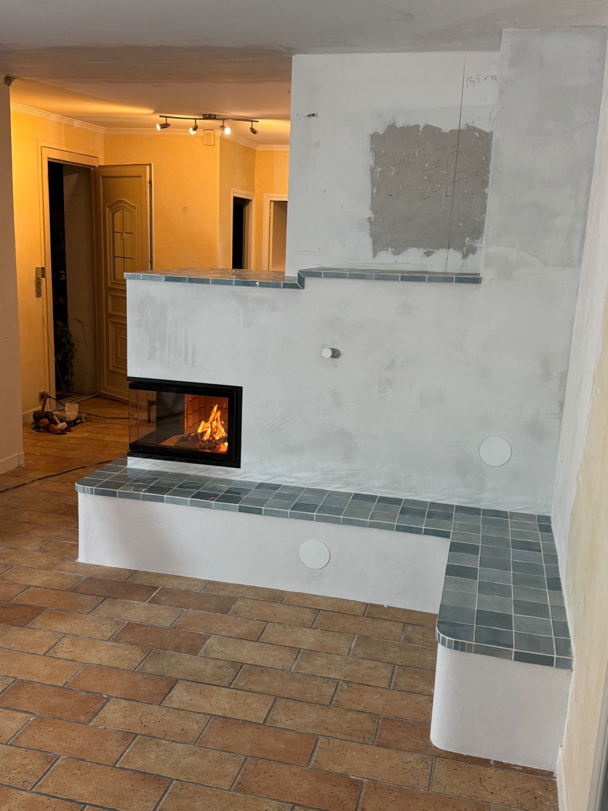 White rendered masonry heater: glazed corner firebox and heated bench tiled in blue-green glazed ceramic