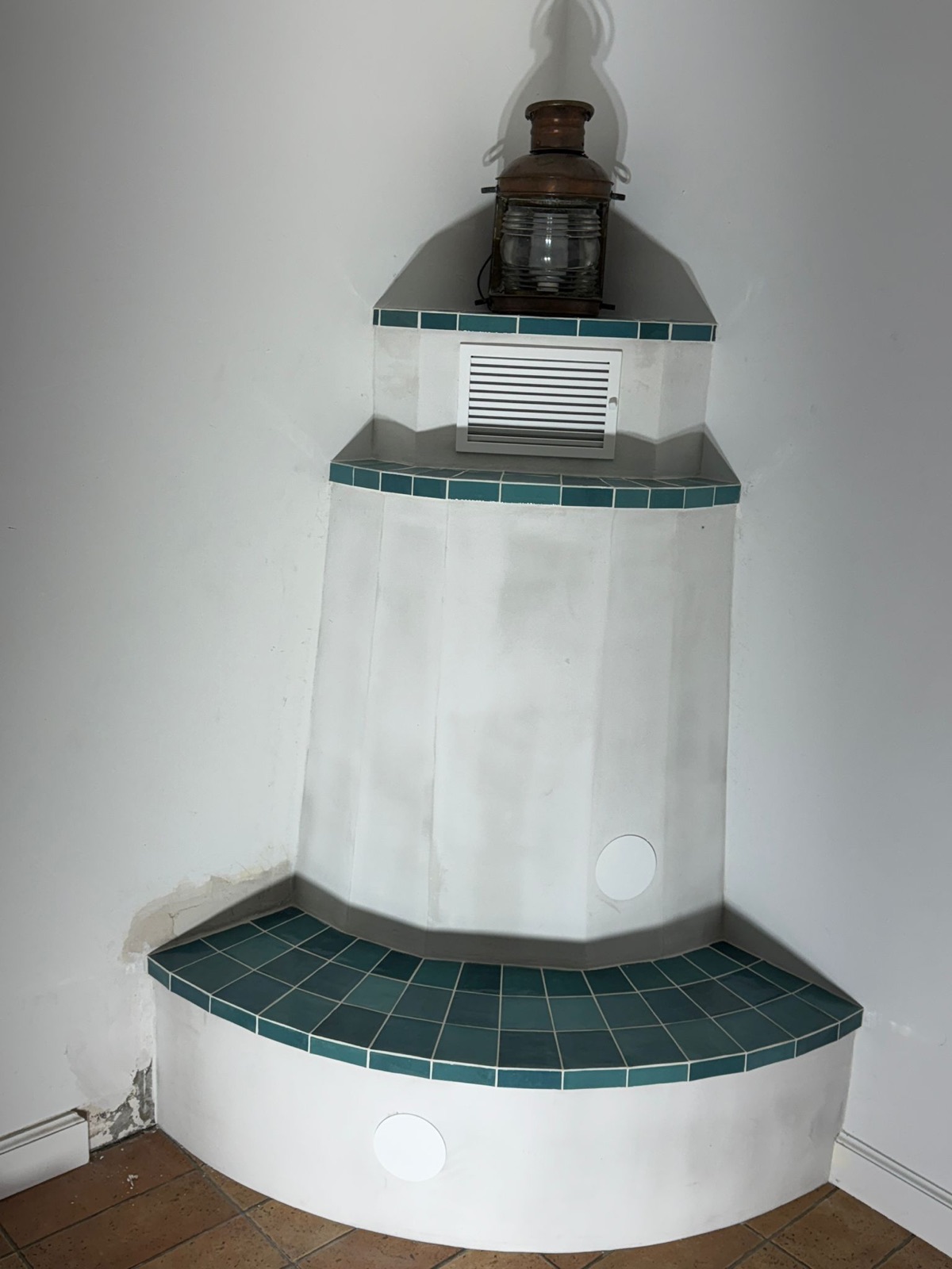 Site-built corner element tiled in turquoise glazed ceramic, with convection grille