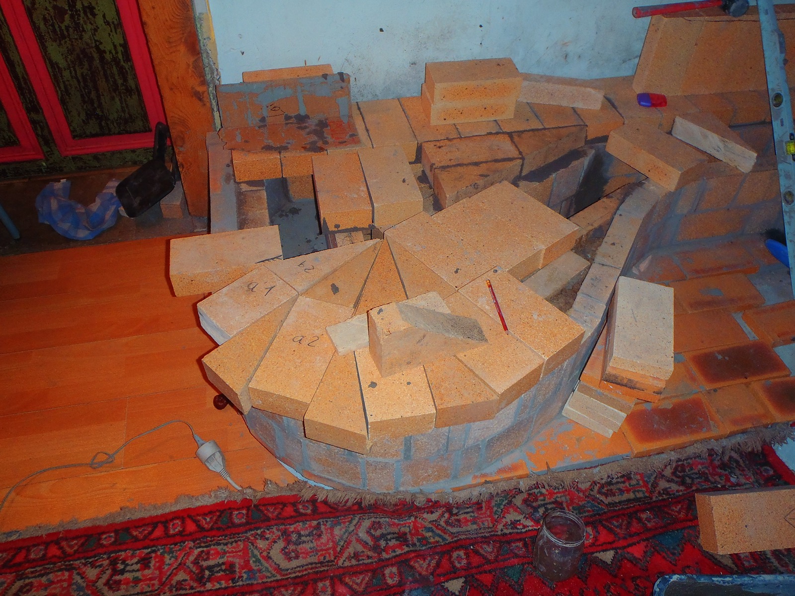 Firebricks cut to a trapezium and numbered in pencil, laid in a ring on the bench during assembly