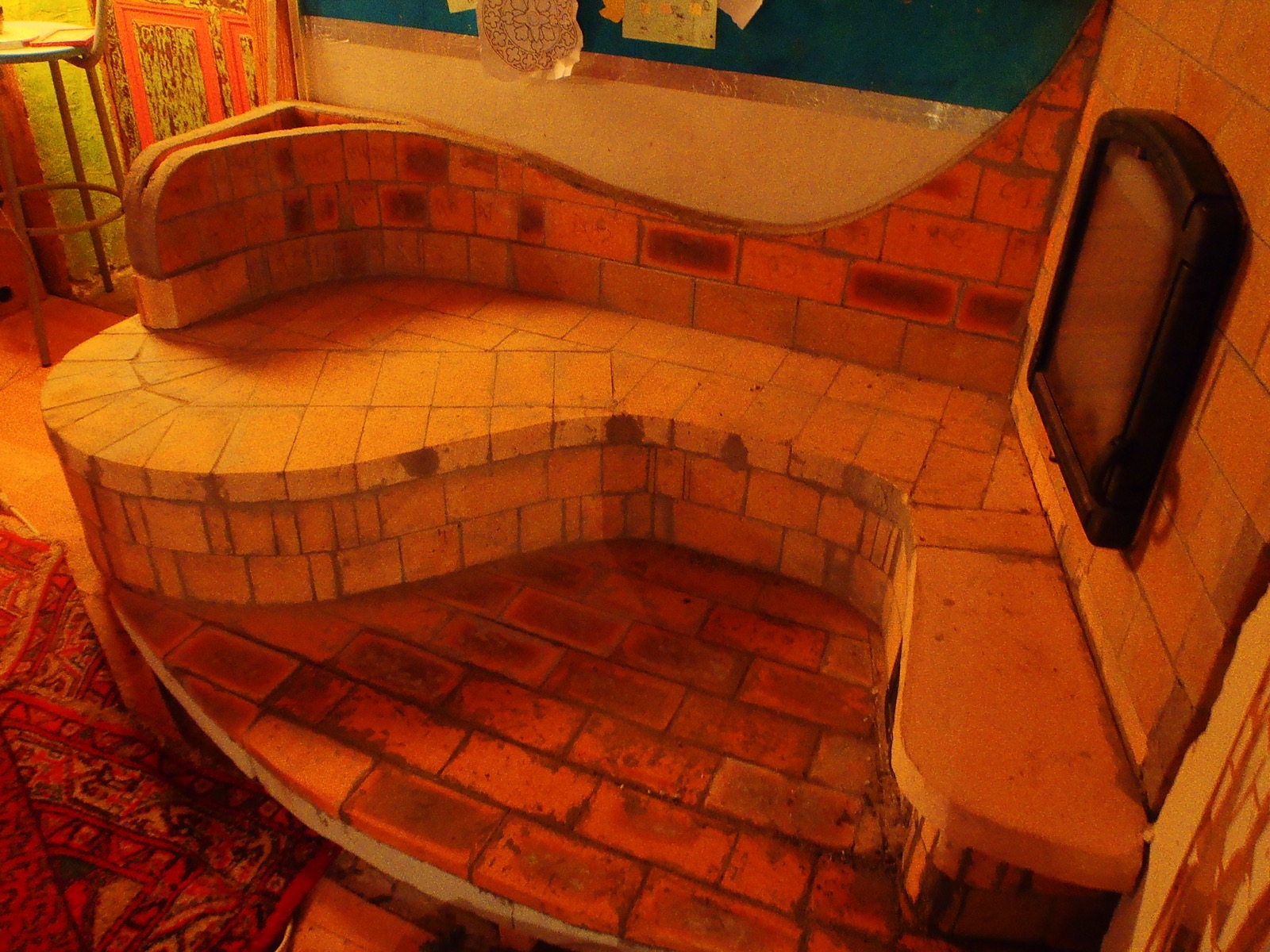 Detail of the heated bench: firebrick seat on two levels, curved backrest, cast-iron cleaning doors on the side