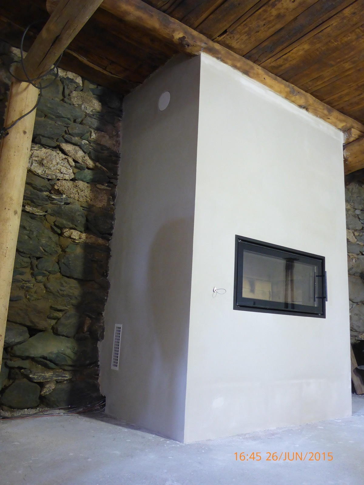 In a stone sheepfold, a horizontal firebox beneath a log-pole roof frame