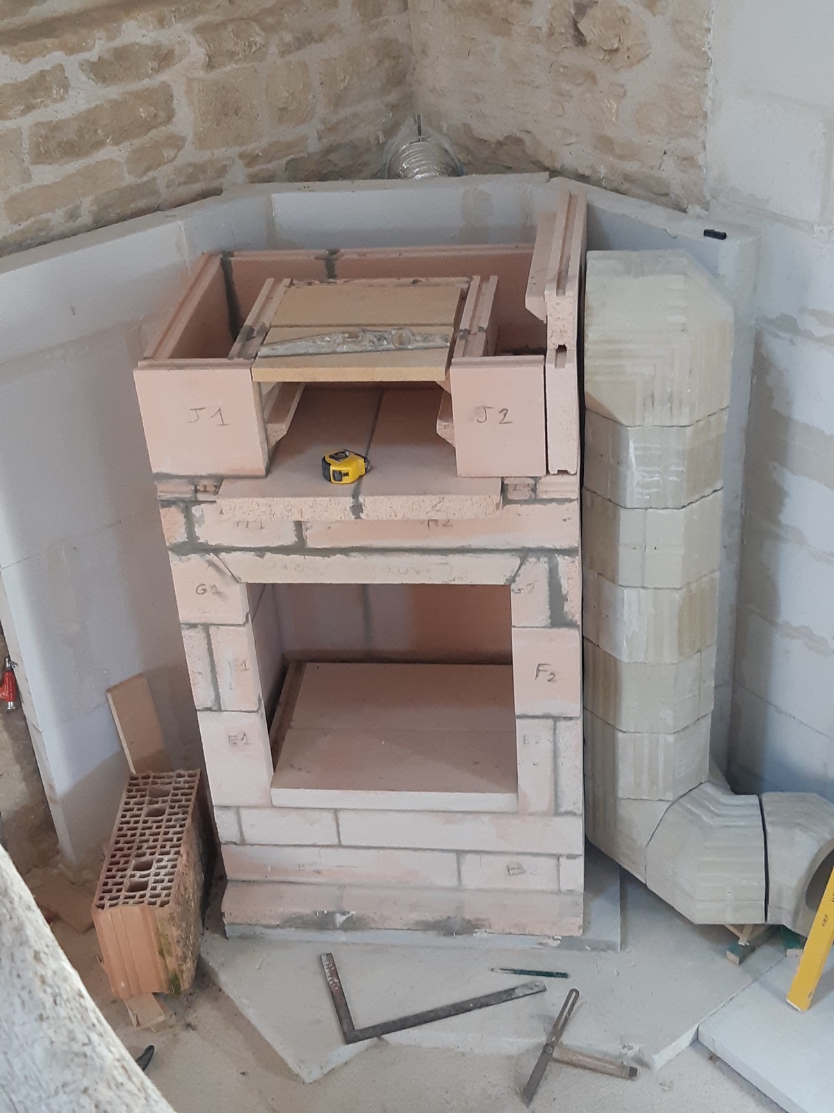 Close-up of the firebox under construction, hearth slab laid, firebrick jambs marked J1 and J2