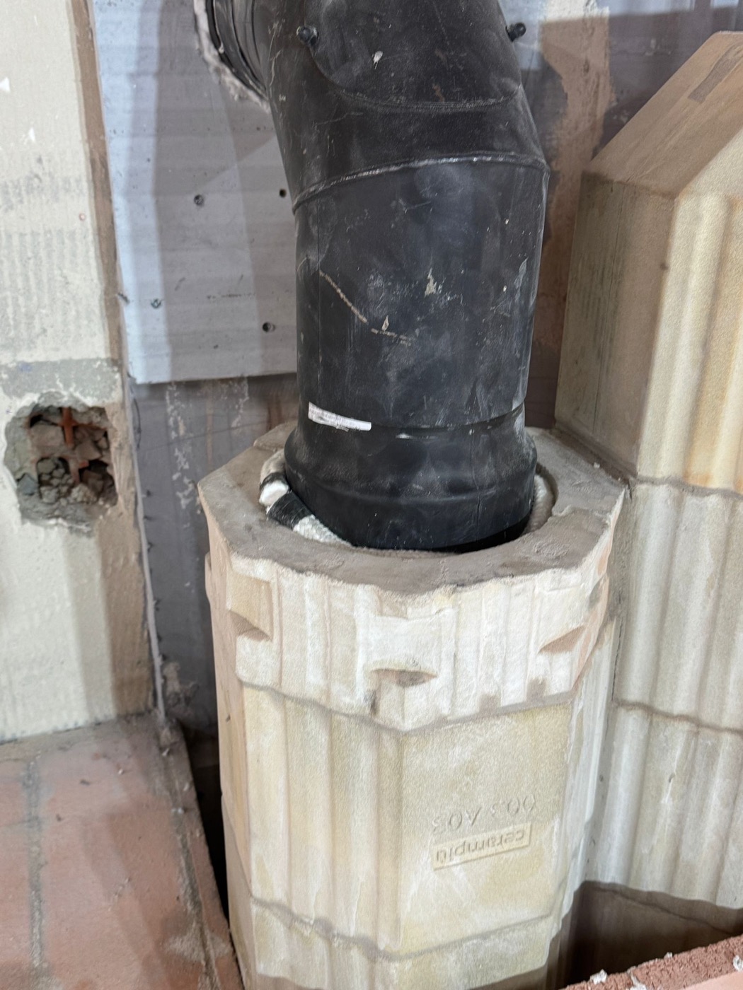 Connection of the black flue pipe to an octagonal ceramic heat-storage element, braided seal visible
