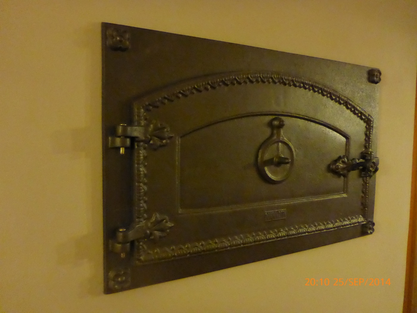 Close-up of the cast-iron oven door: beaded moulding, corner rosettes, swivelling ring handle