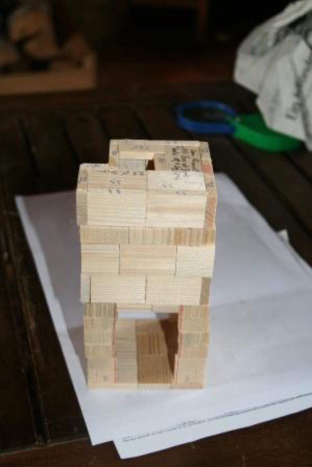 Wooden model of a masonry heater placed on drawings, showing the inside of the heater core and the flue path