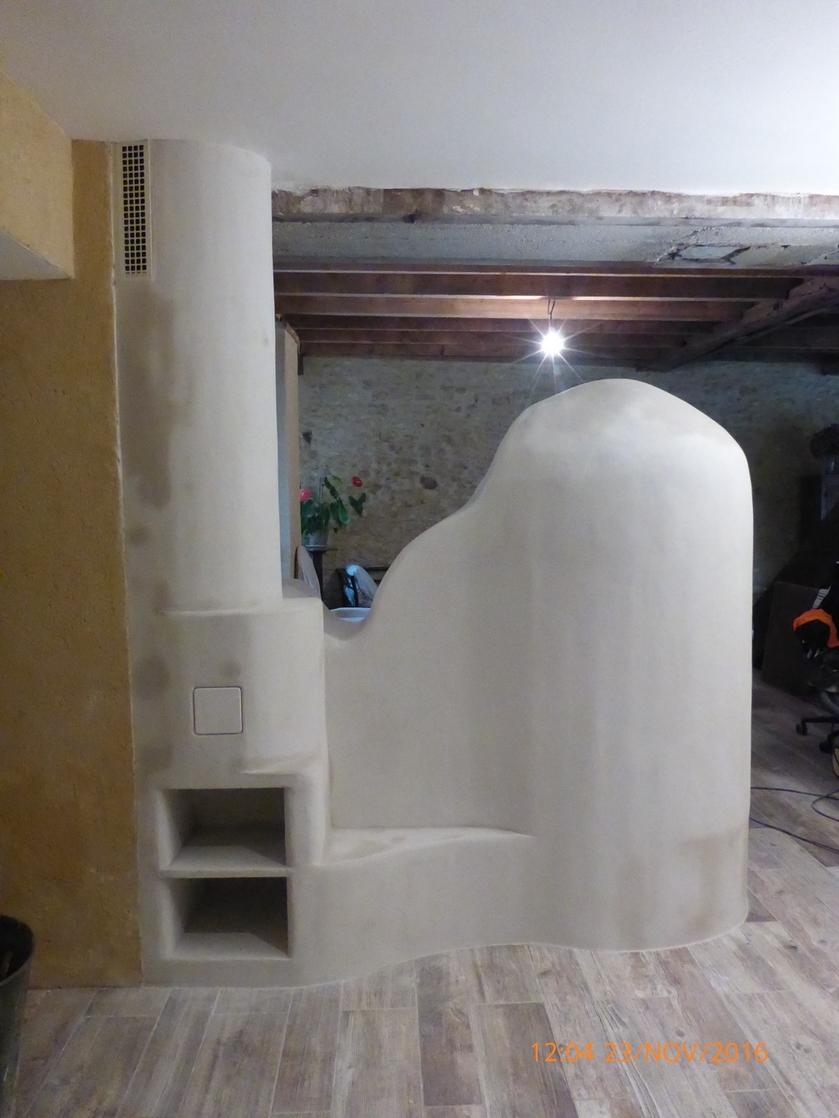 The other side of the masonry heater, with its rounded silhouette, a rising column and two square storage niches built into the mass