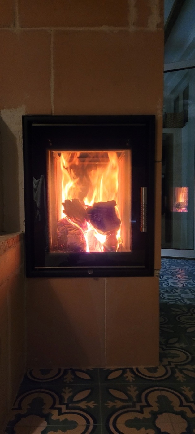 Lively burn in the glazed firebox of the masonry heater, seen from the front on the cement tile floor