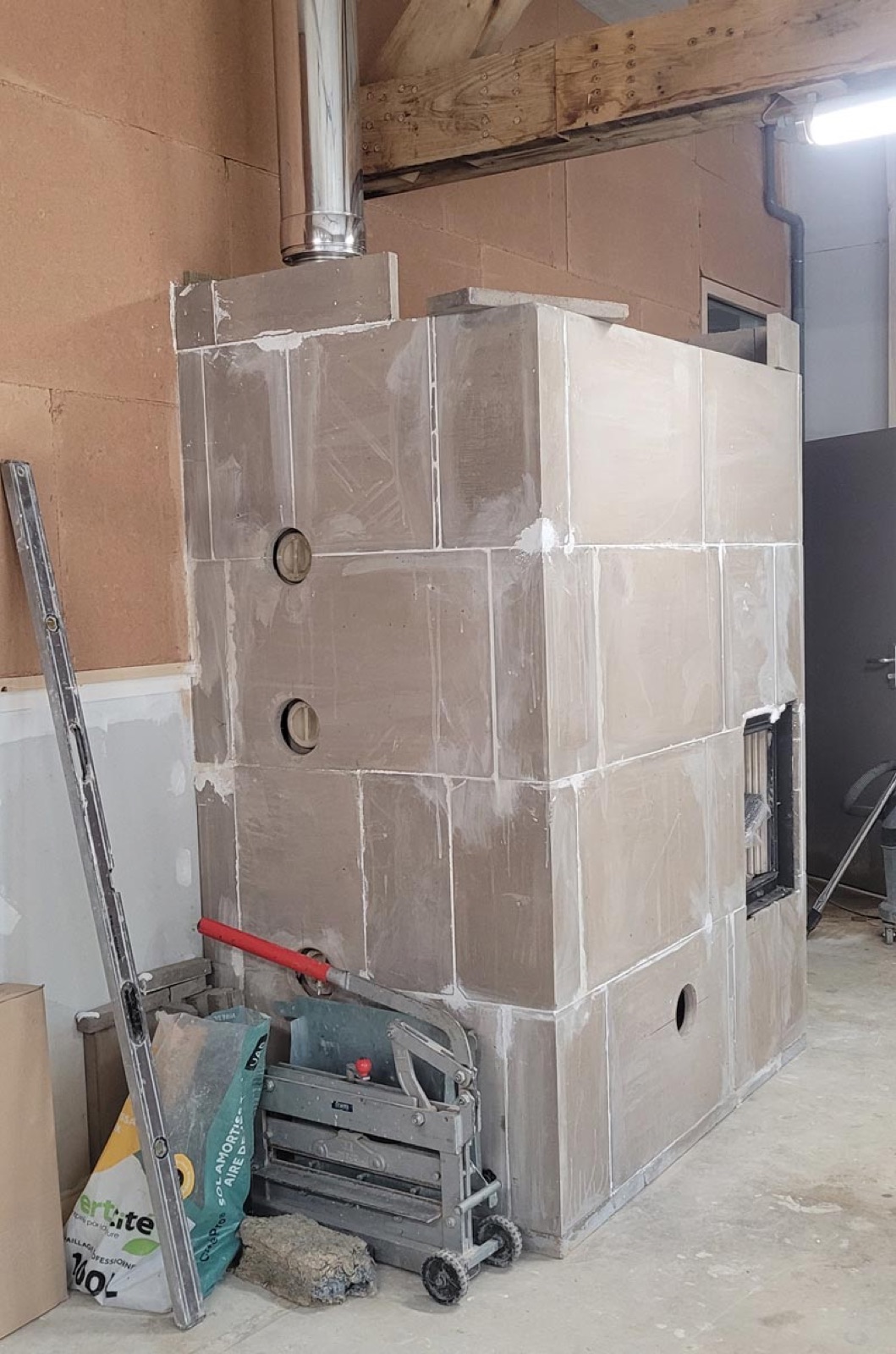 Assembly of the nursery-school heater's cladding in sand-lime blocks, under the roof structure