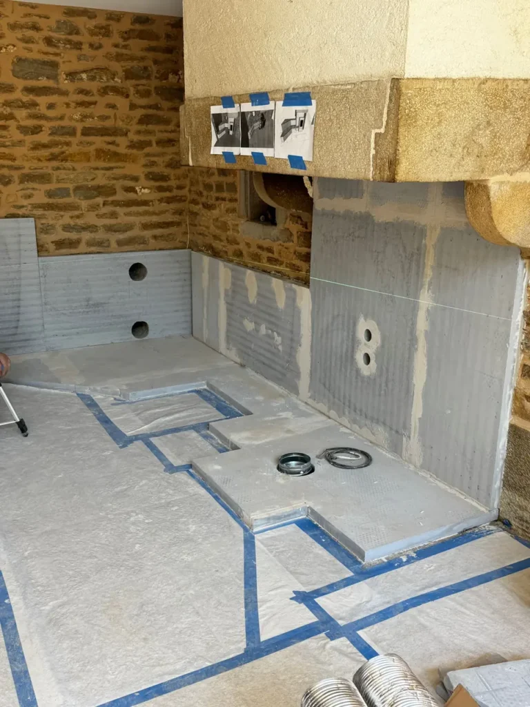 Preparing the masonry heater in the old fireplace: insulation boards on the walls and the bench outline marked on the floor