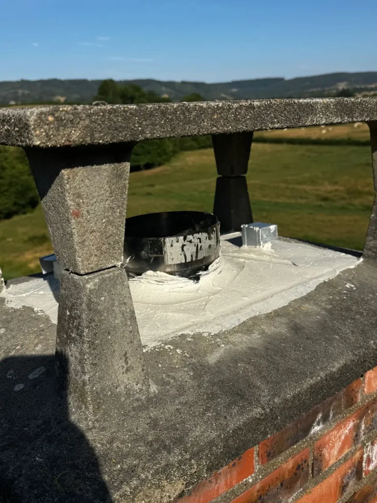Stainless-steel liner emerging at the top of the chimney stack, beneath the chimney cap