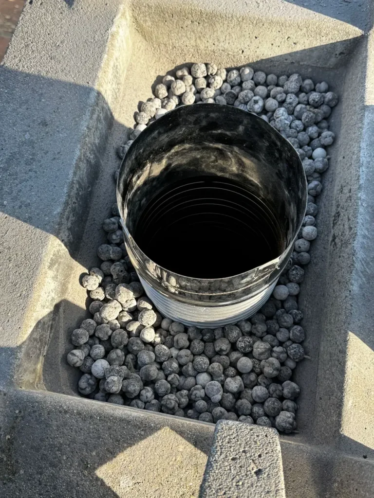 Stainless-steel flue liner in the old fireplace flue, embedded in bead insulation