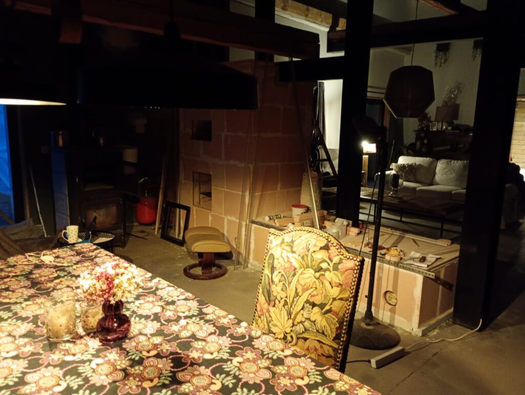 The masonry heater under construction in the middle of the living room, beneath a half-timbered roof structure